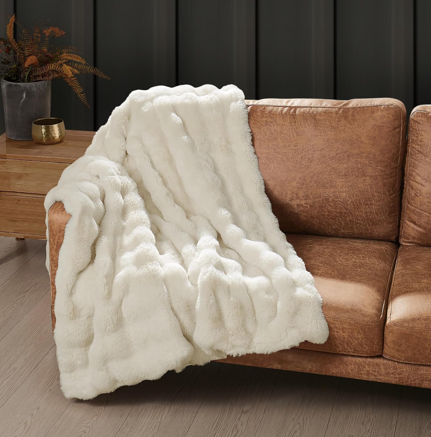 Frye Bubble Rabbit faux fur throw in Ivory over a cognac leather sofa, pale pile showing clear highlights and shadows